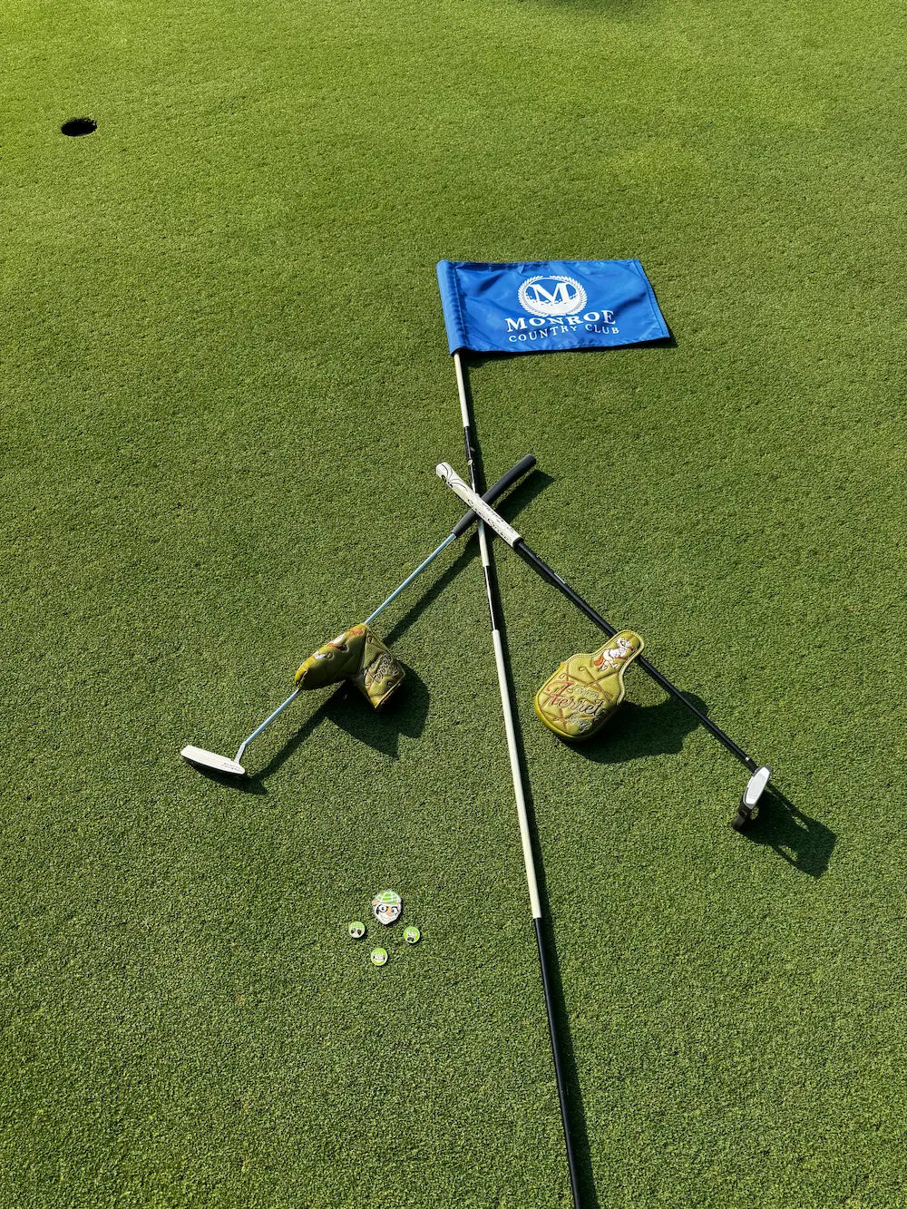 Collection of Green Ferret Golf Accessories laying on the Monroe Country Club flagstick