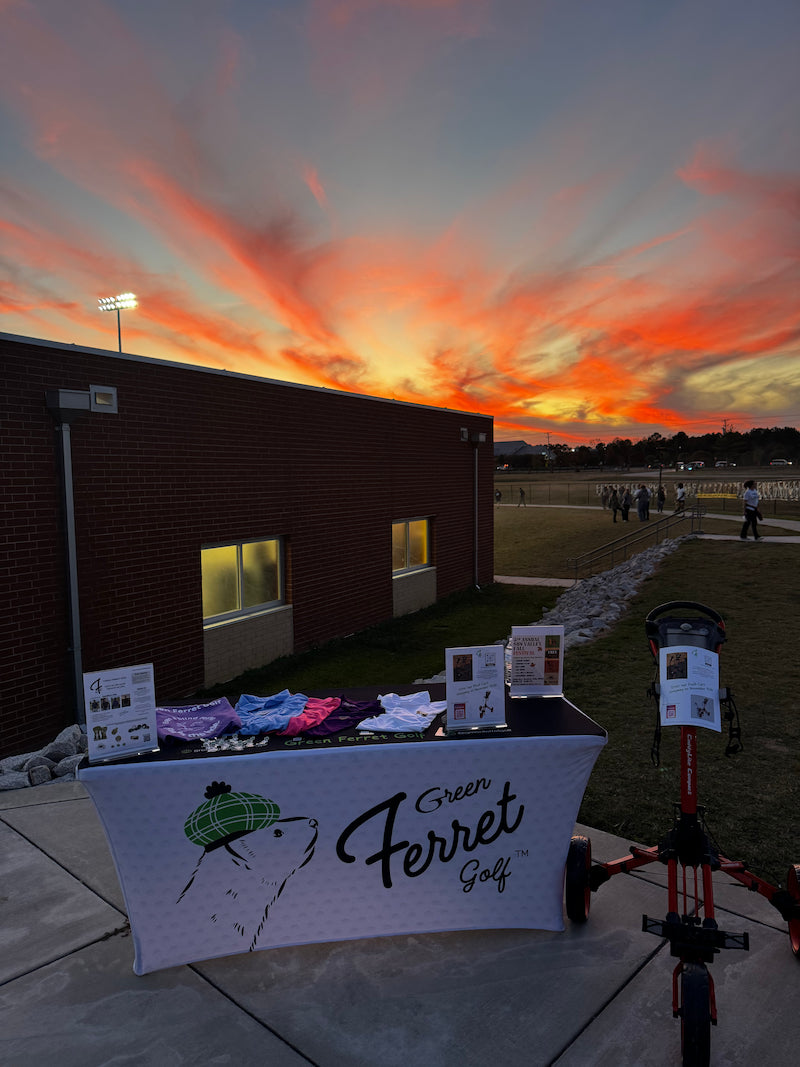 Table with 'Green Ferret Golf' branding at sunset at the Sun Valley Spartans High School football stadium in Indian Trail, NC