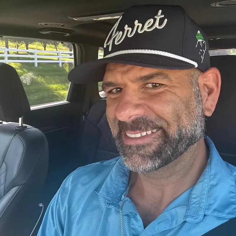 Man wearing a cap with 'Ferret' branding inside a vehicle
