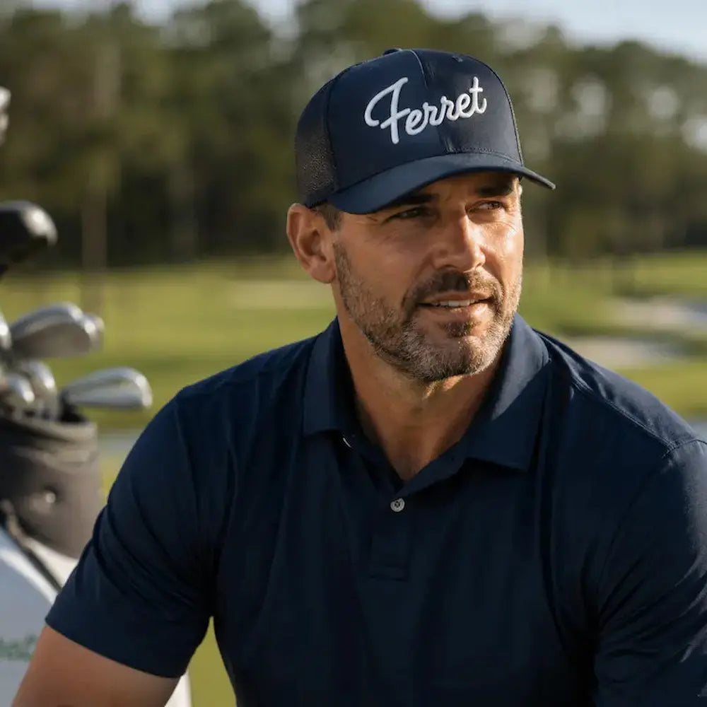 Man wearing a navy blue cap with 'Ferret' logo and matching polo shirt on a golf course.