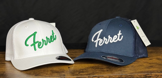 Two hats with 'Ferret' branding on a wooden surface against a black background