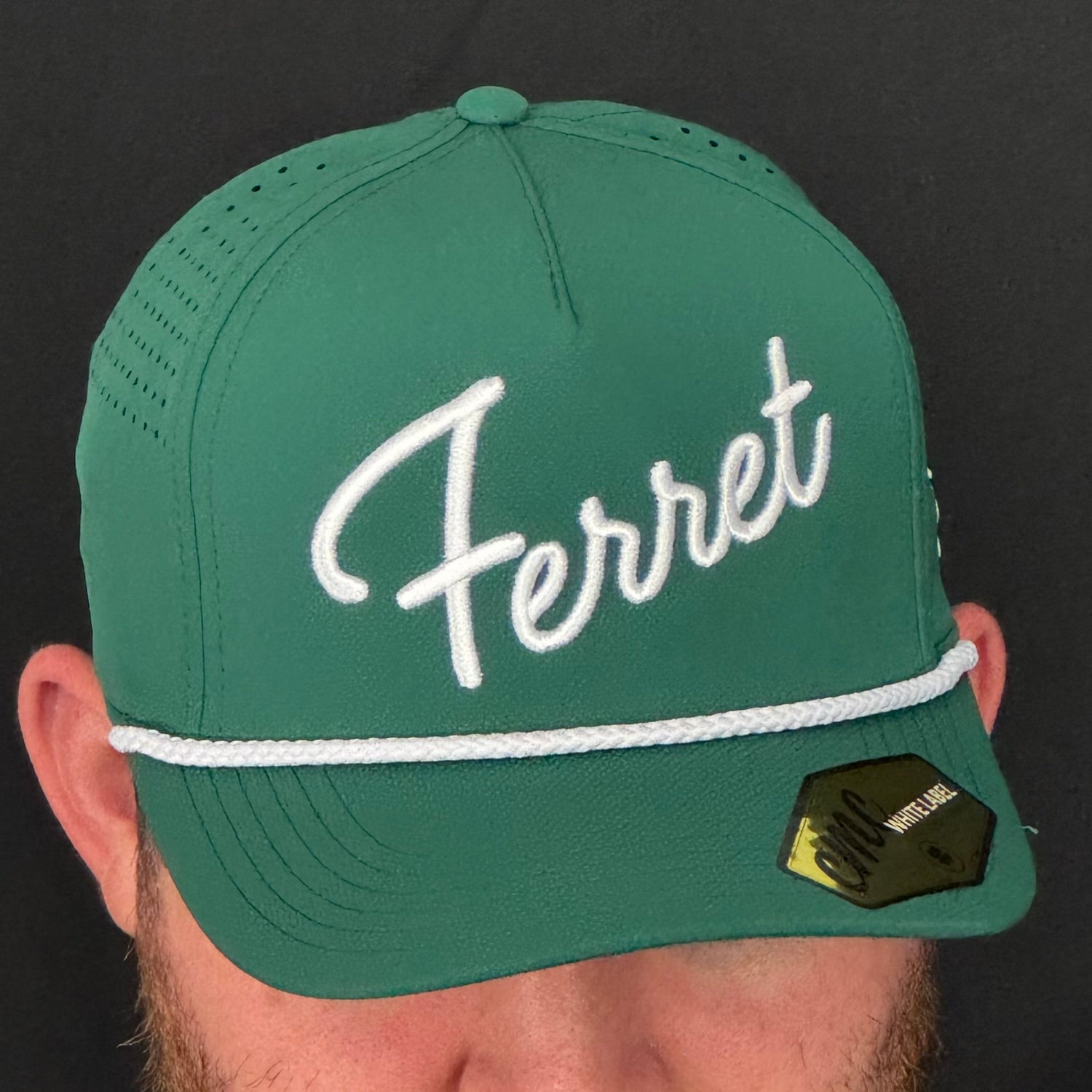 Green cap with 'Ferret' logo worn by a person against a black background