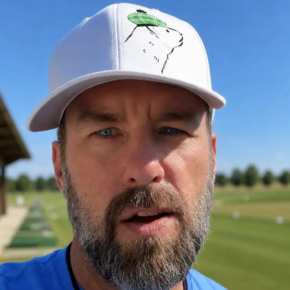Man wearing a white cap with a trademarked Ferret Golf logo on a golf course