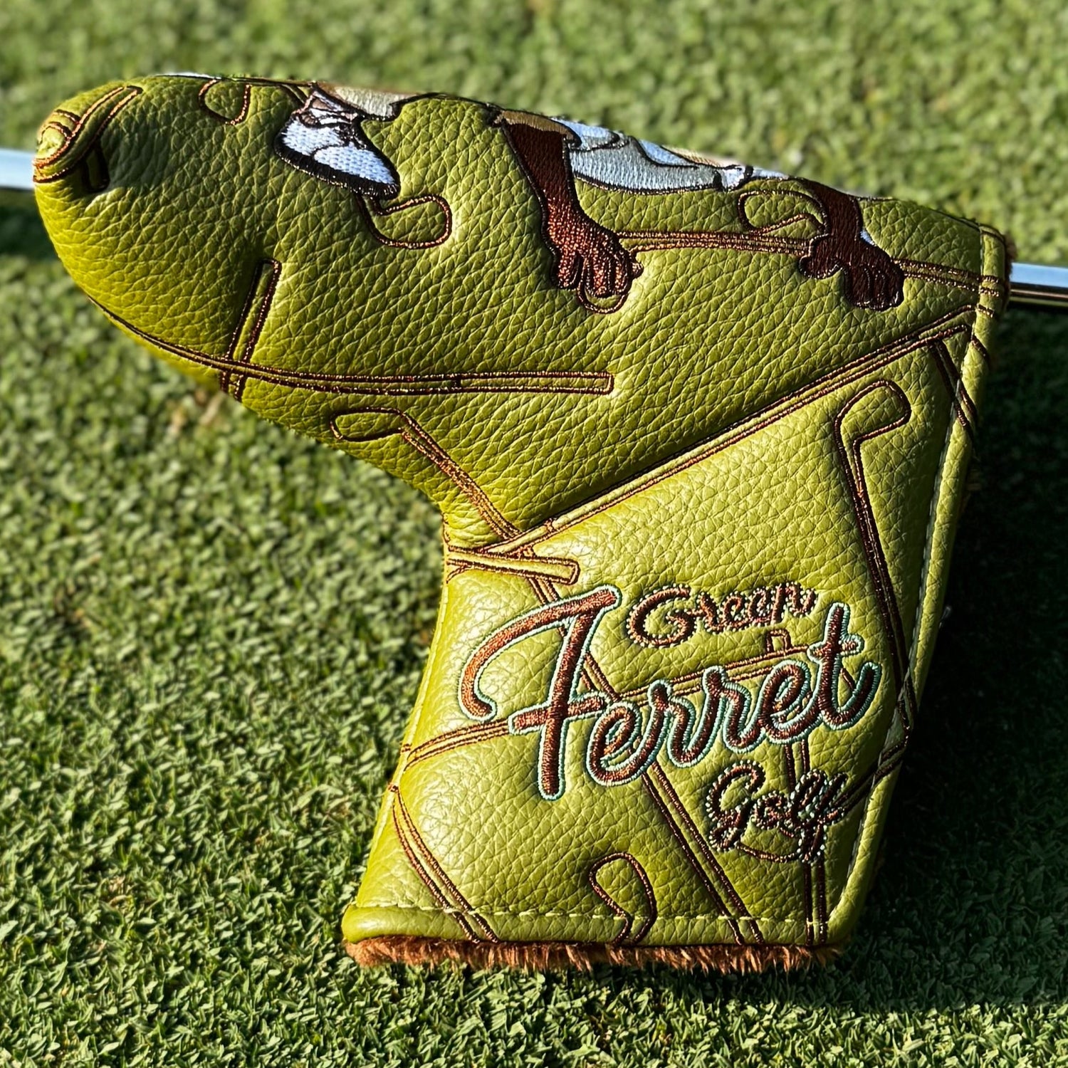 Green golf club head cover with 'Green Ferret Golf' branding on a green grass background