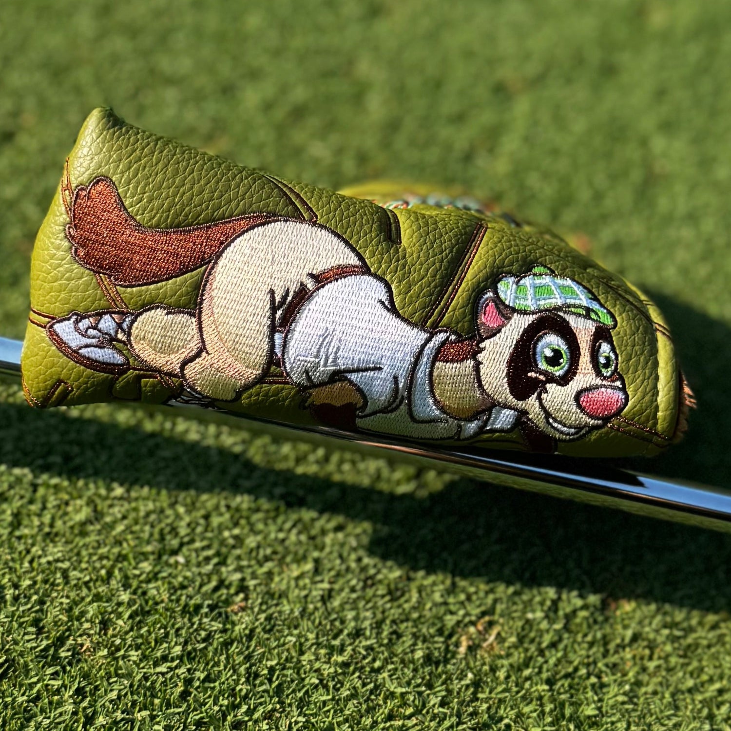Golf club head cover with cartoon character on a green grass background