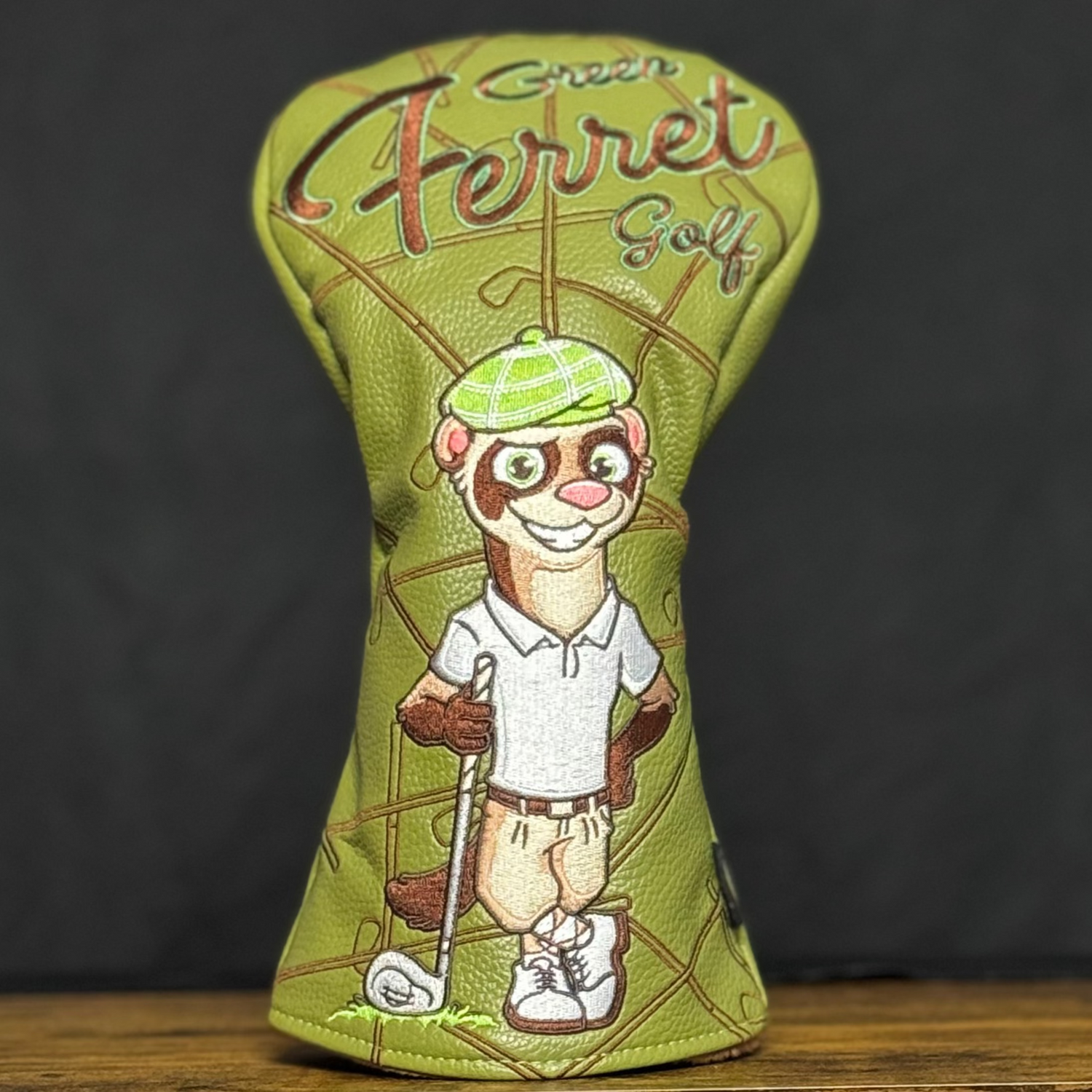 Green Ferret Golf Branded Driver Head cover with cartoon ferret design on a wooden surface