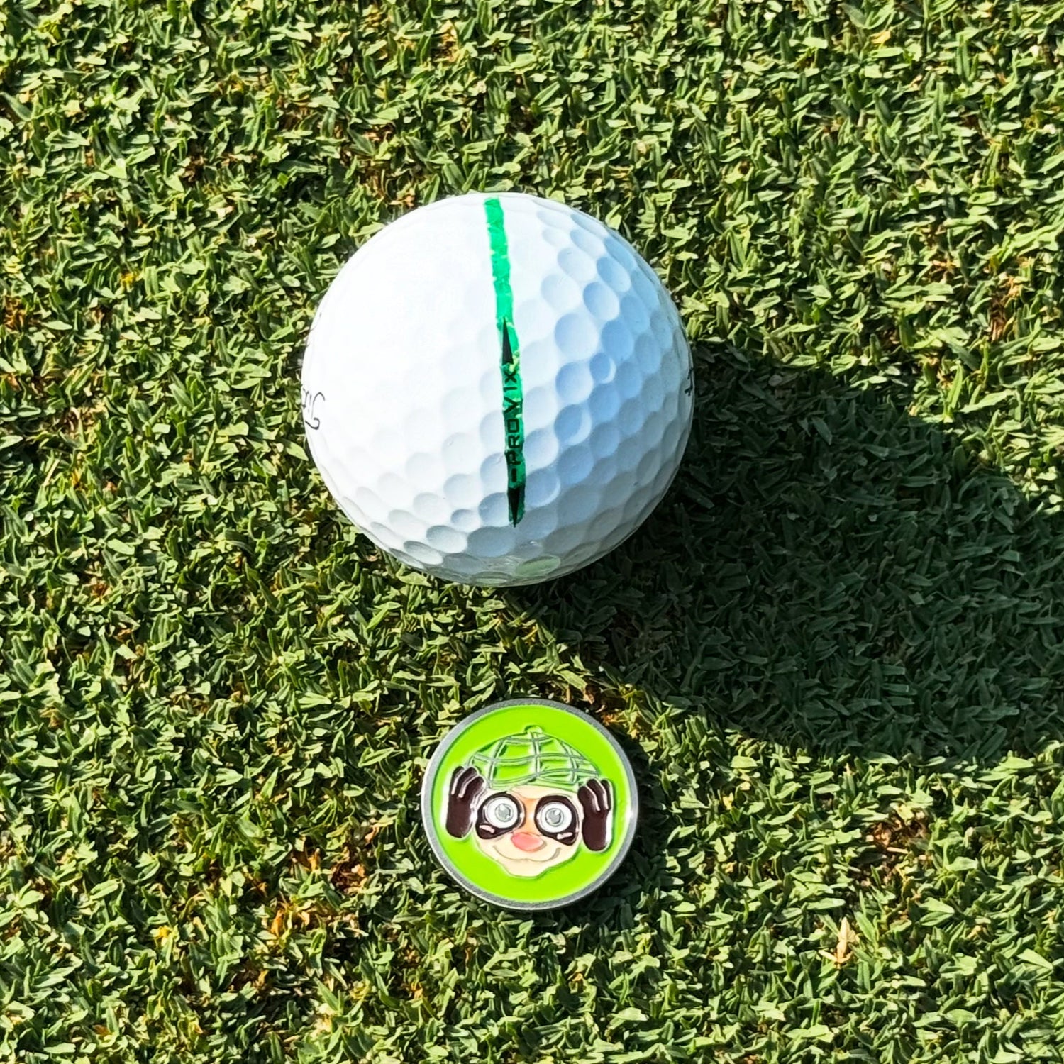 Circular ball marker with a stylized Finneus Ferret Hear No Bad Shots  Ball Marker with 'Green Ferret Golf' branding 