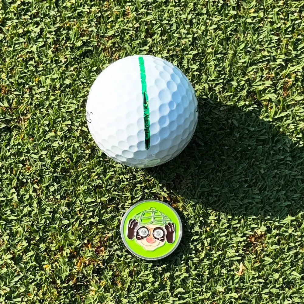 Finneus Ferret "Hear No Bad Shots" ball marker next to a Titliest golf ball