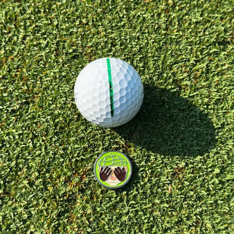 Finneus Ferret "See No Bad Shots" ball marker next to a Titliest golf ball