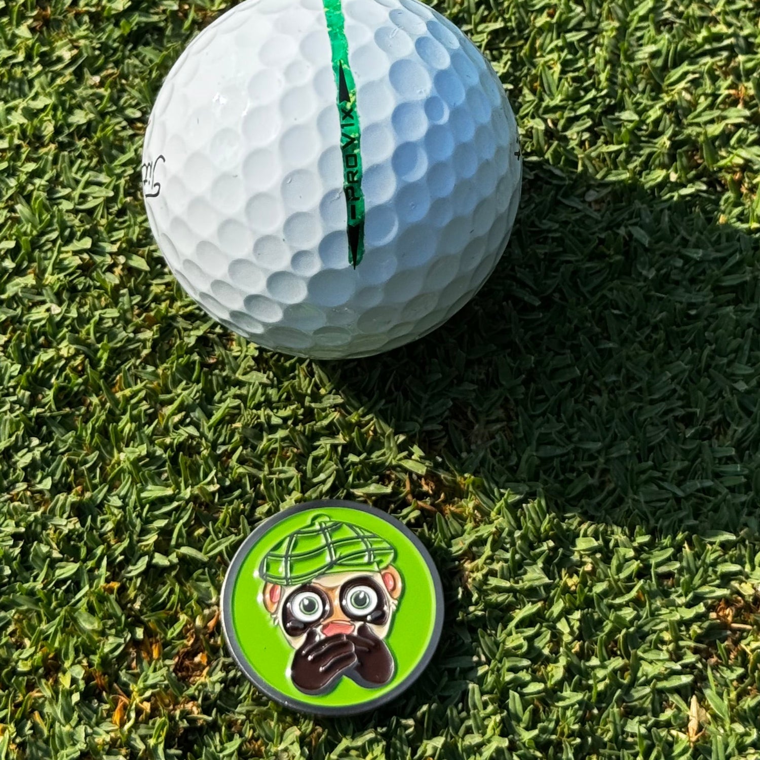Circular ball marker with a stylized Finneus Ferret Speak No Bad Shots 