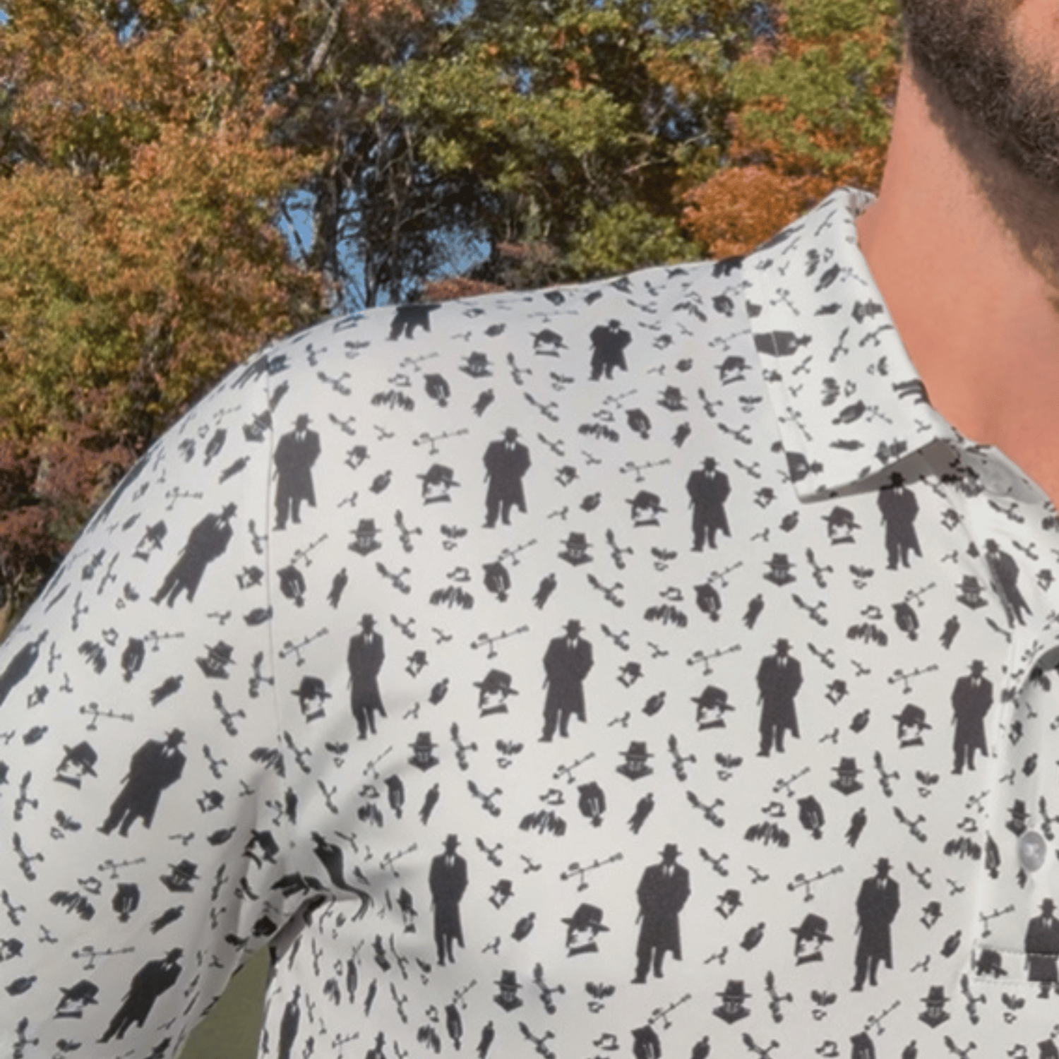 close up of a White performance golf polo from Green Ferret Golf featuring American Mobster Imagery and golf push carts in a pattern.