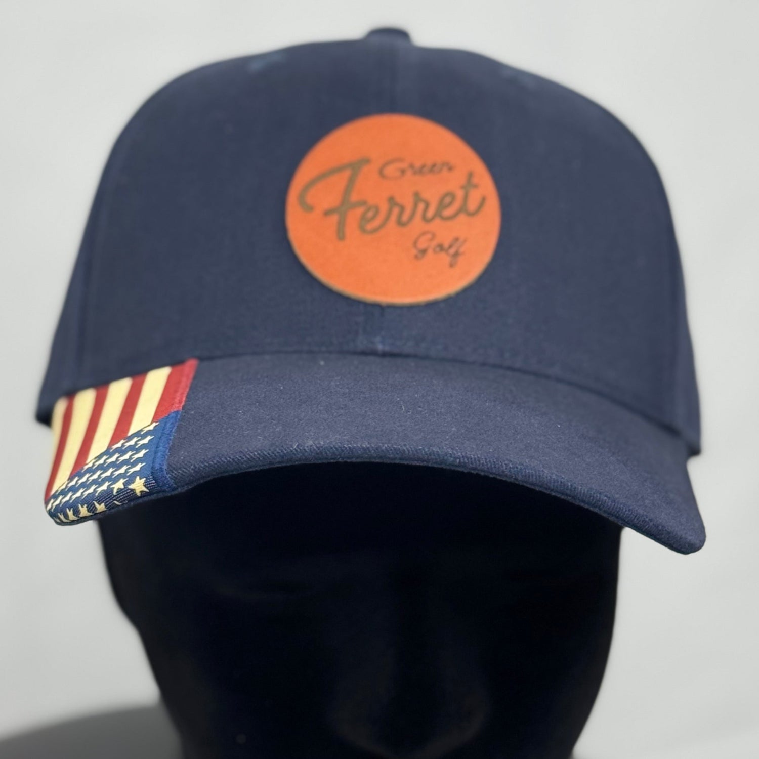 A navy blue structured baseball cap with a cognac colored leather patch featuring the text 'Team USA' on the front, and a USA flag on the visor.