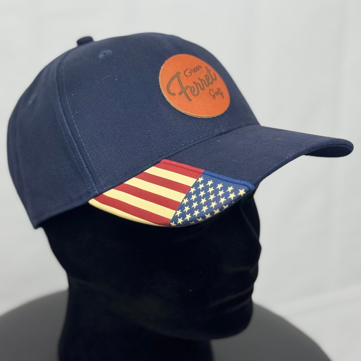 Navy blue cap with American flag patch on a mannequin head against a gray background