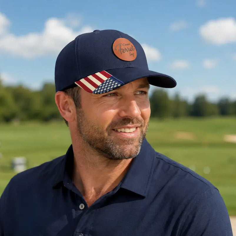 Man wearing a navy cap with an American flag design and trademarked Green Ferret Golf patch on a golf course